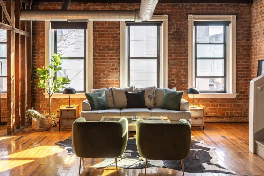 a living room with a couch and a brick wall at Stunning Loft in the heart of OTR in Cincinnati