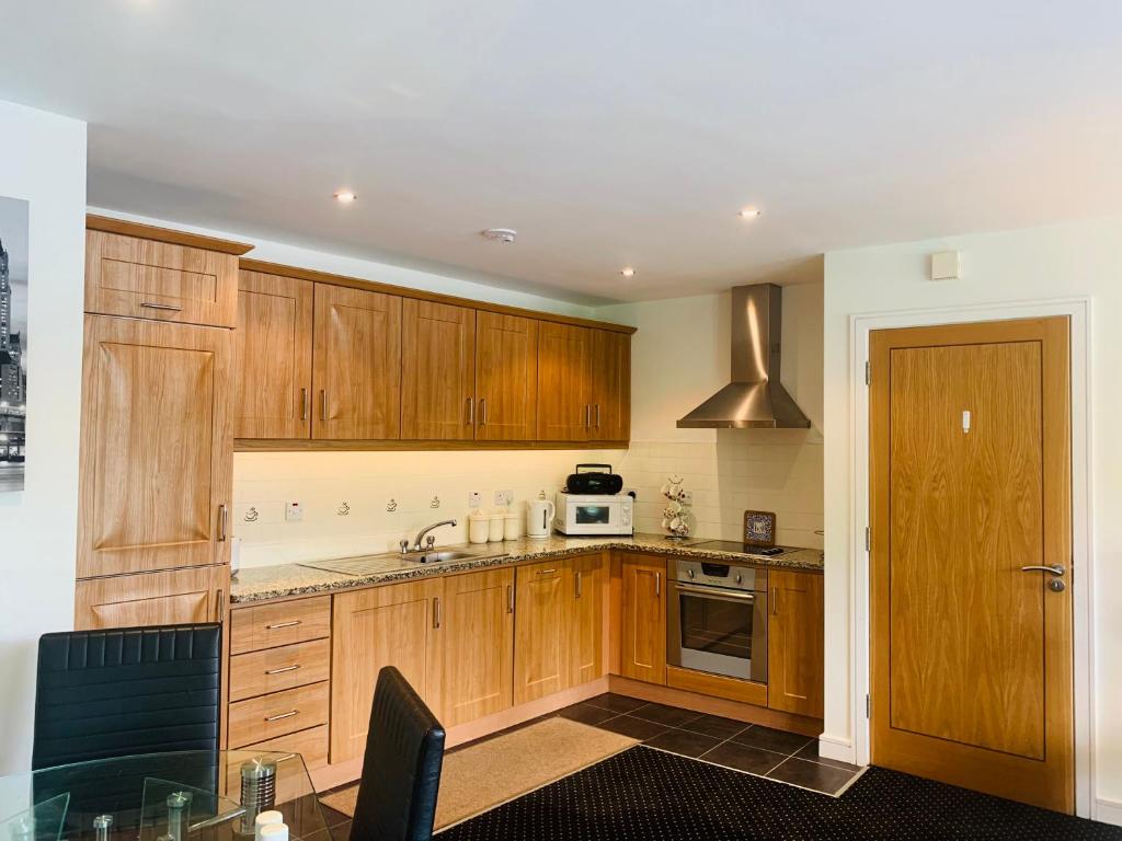 a kitchen with wooden cabinets and a sink and a microwave at Courthouse View Penthouse in Clifden