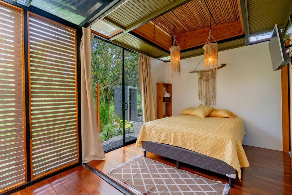 a bedroom with a bed and a large window at Tiny garden house in Turrialba
