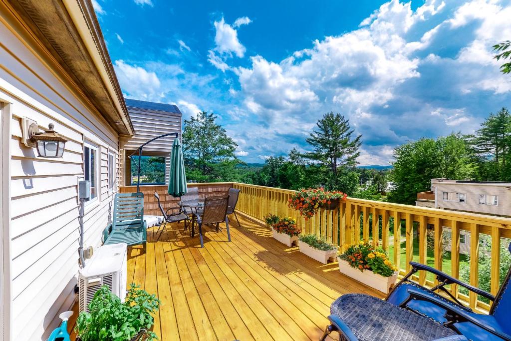 a wooden deck with chairs and an umbrella at Mountainside Resort F401 in Stowe