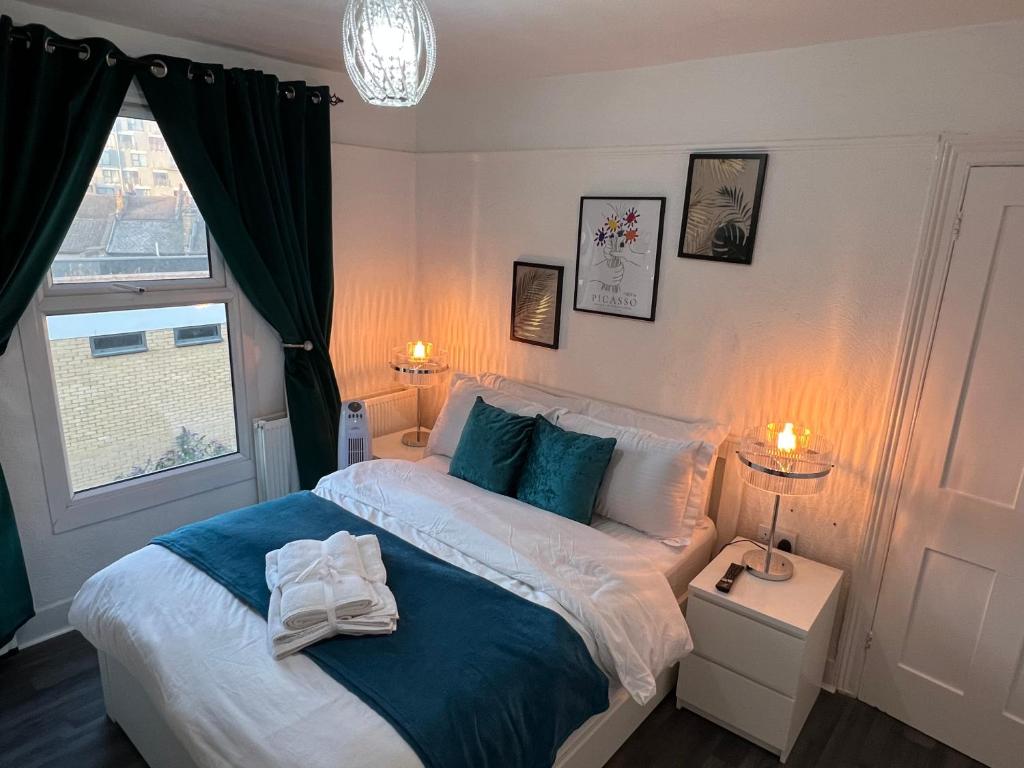 Schlafzimmer mit einem Bett mit blauer und weißer Bettwäsche und einem Fenster in der Unterkunft Luxury 1Bed Holiday Flat-10 Minutes from London Bridge & 3Mins walk to Lewisham DLR in London