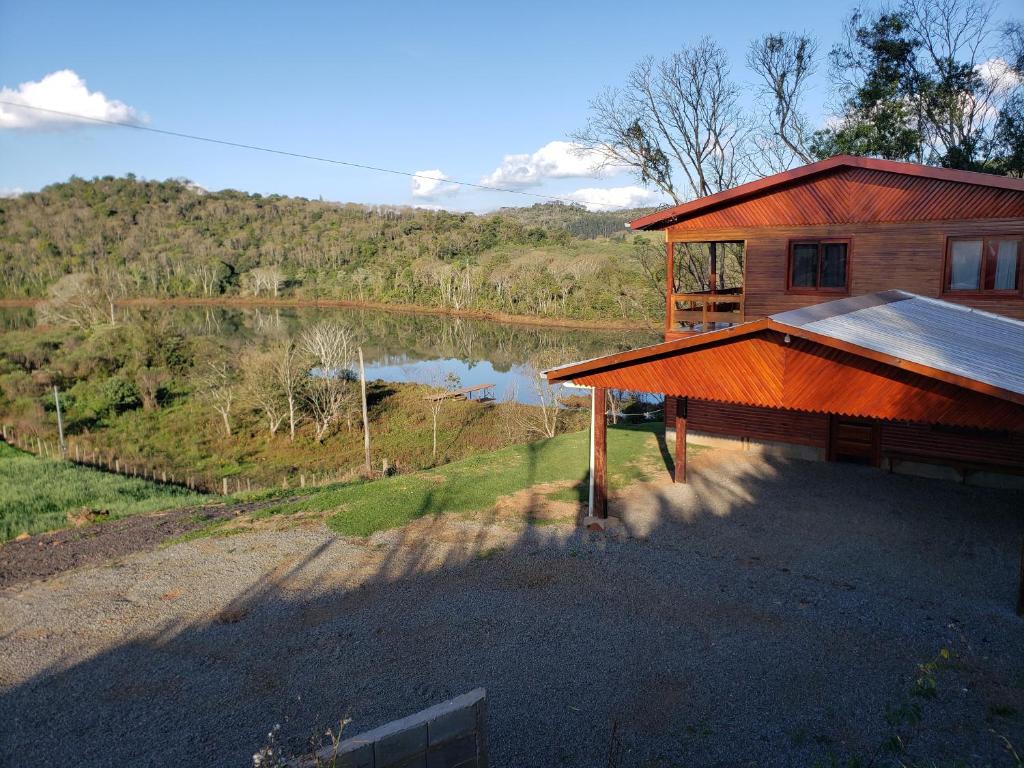 a cabin with a view of a lake and a house at Casa rústica às margens do lago 