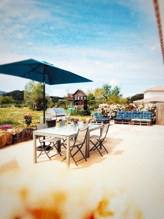 une table et des chaises avec un grand parapluie bleu dans l'établissement A PIAZZOLA, à Petreto-Bicchisano