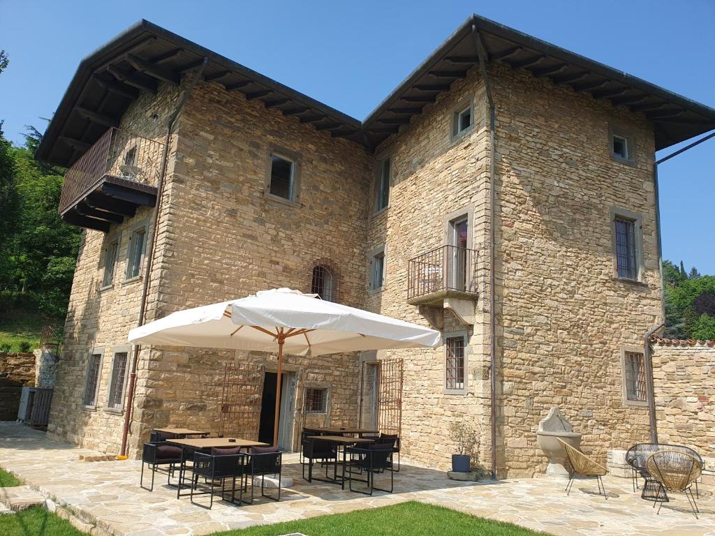 a large brick building with tables and an umbrella at Foresteria Antica Bastia B&B in Bergamo