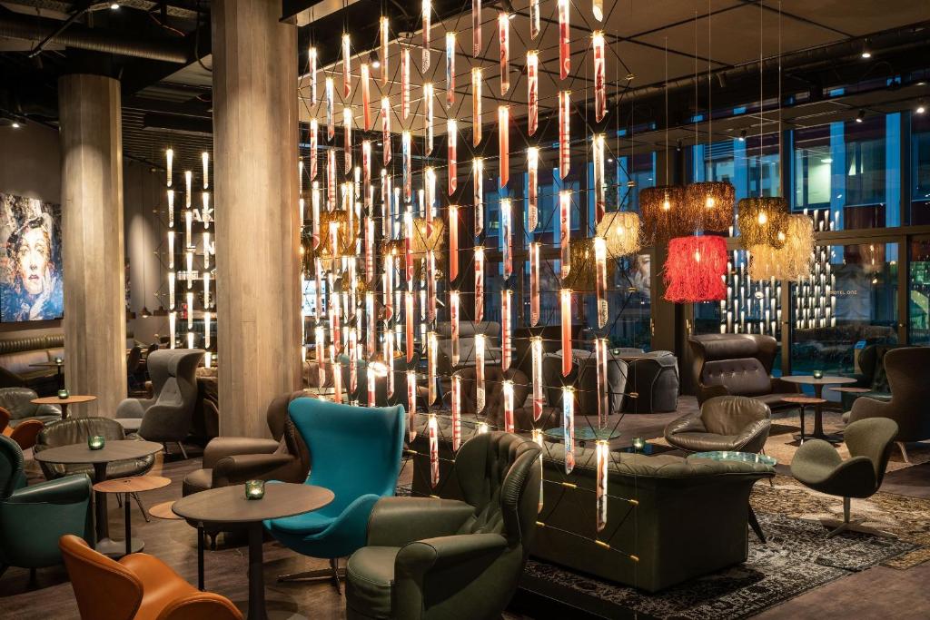 a lobby with chairs and tables and a chandelier at Motel One Berlin-Spittelmarkt in Berlin