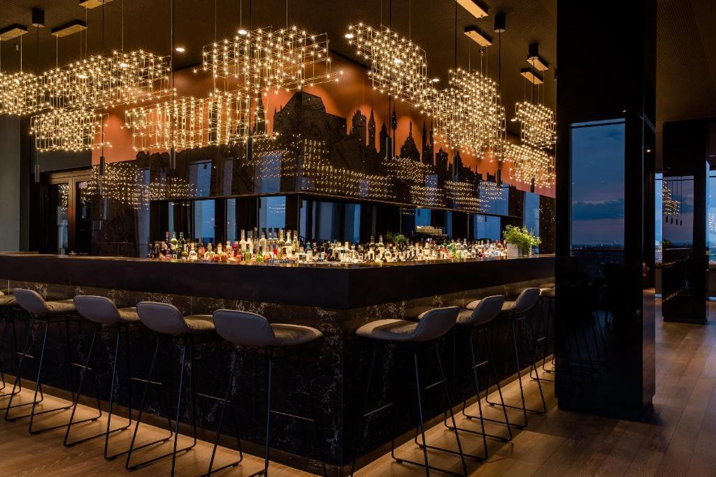 um bar com um monte de luzes e bancos em The Cloud One Nürnberg, by the Motel One Group em Nurembergue