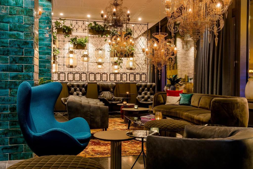 eine Lobby mit einem blauen Stuhl, Sofas und Tischen in der Unterkunft Motel One München-Haidhausen in München