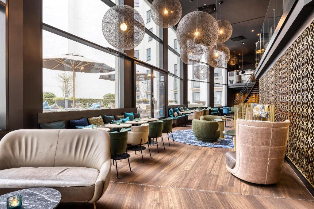 een restaurant met stoelen en tafels en grote ramen bij Motel One Brussels in Brussel