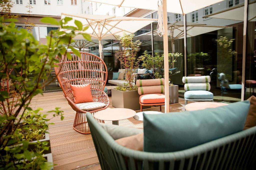 eine Terrasse mit Stühlen, Tischen und einem Sonnenschirm in der Unterkunft Motel One Hannover-Oper in Hannover