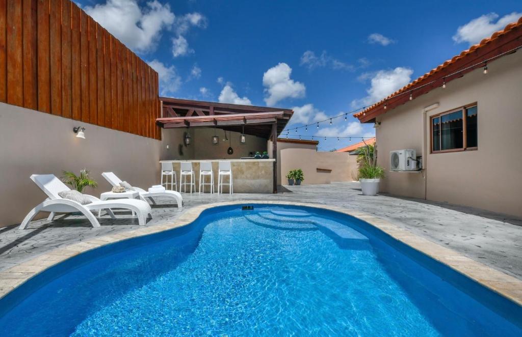 - une piscine avec des chaises et une maison dans l'établissement Felicidad 30, à Oranjestad