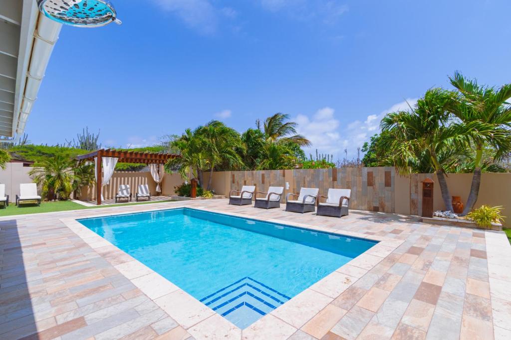 a swimming pool in a yard with chairs and trees at Topaz 8 in Palm-Eagle Beach
