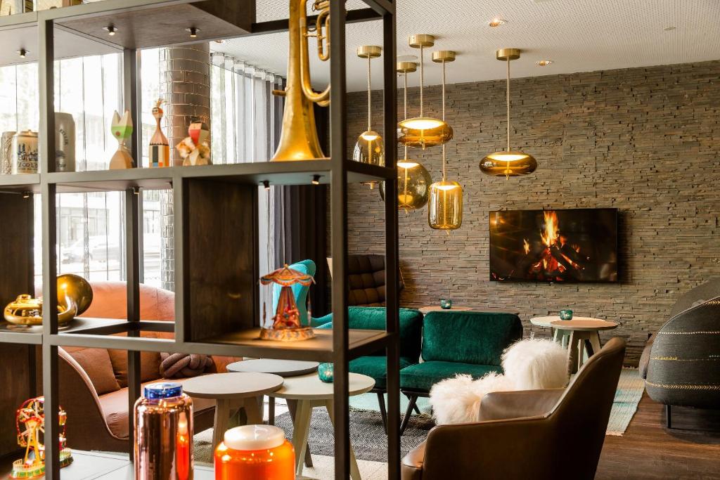 eine Lobby mit einem Sofa, Stühlen und einem Kamin in der Unterkunft Motel One München-Westend in München