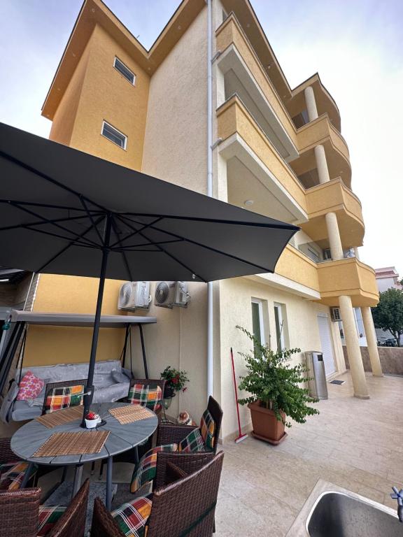 een patio met een tafel en stoelen en een parasol bij Apartments Edona in Ulcinj