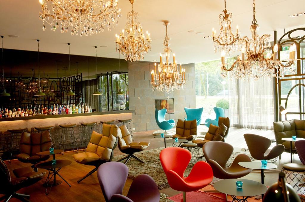 a lobby with chandeliers and chairs and a fireplace at Motel One Amsterdam in Amsterdam