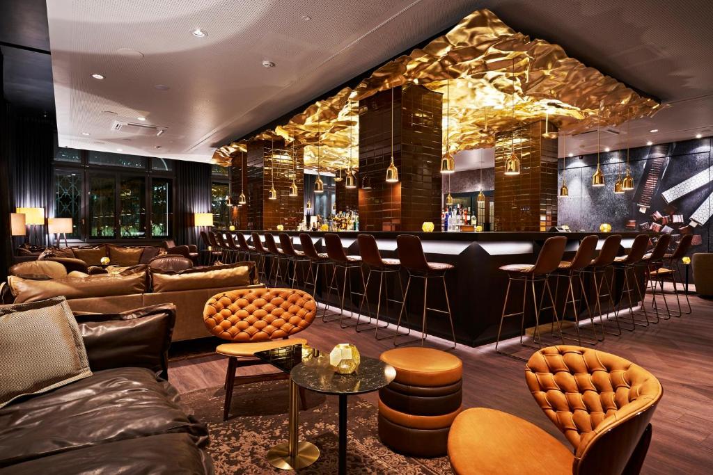 a bar with couches and chairs in a room at Motel One Zürich in Zurich