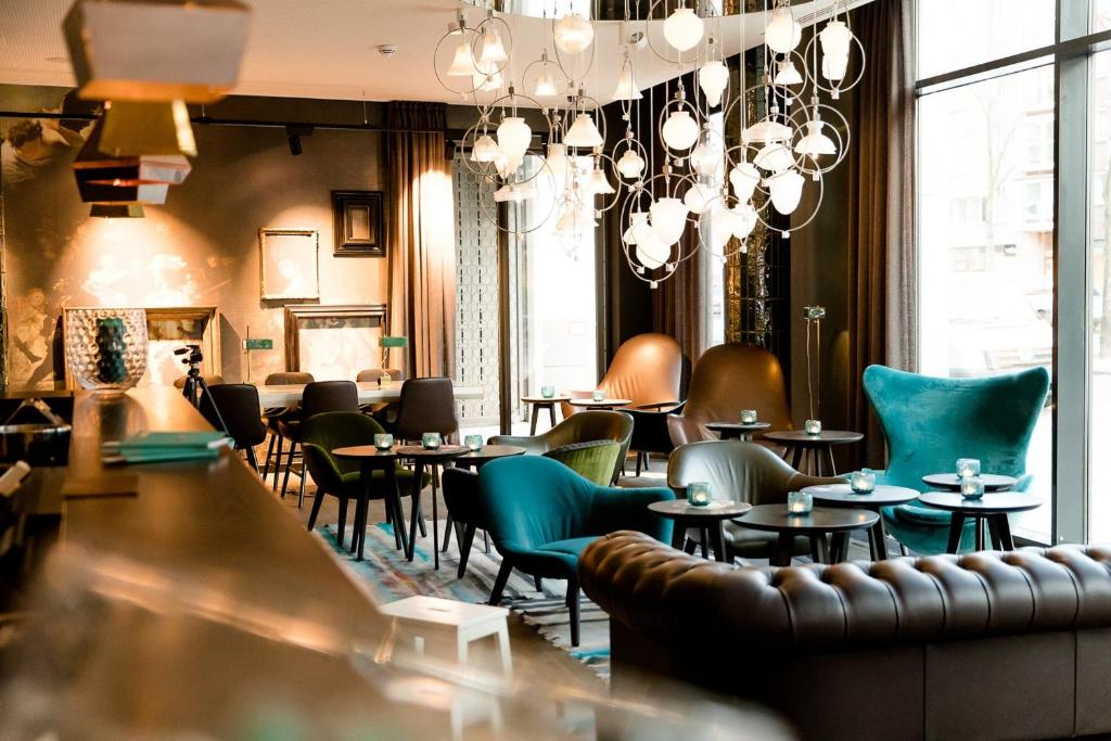 a restaurant with tables and chairs and chandeliers at Motel One Amsterdam-Waterlooplein in Amsterdam