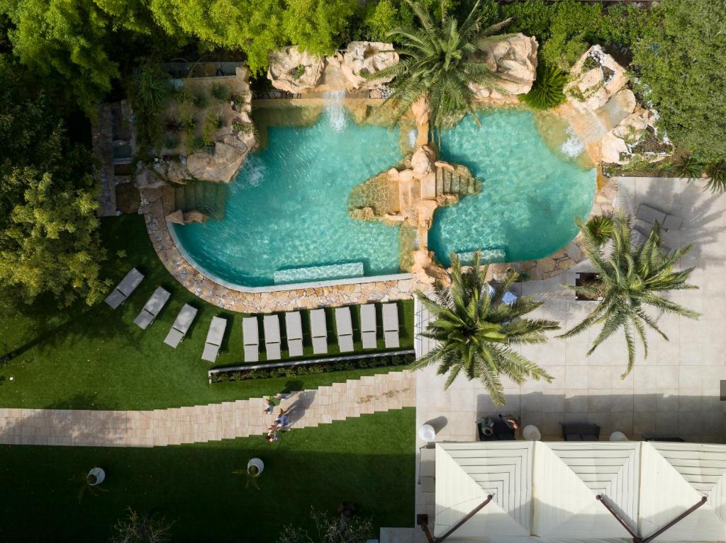 einen Blick über einen Pool mit Palmen in der Unterkunft Hotel Capanna d'Oro in Lignano Sabbiadoro