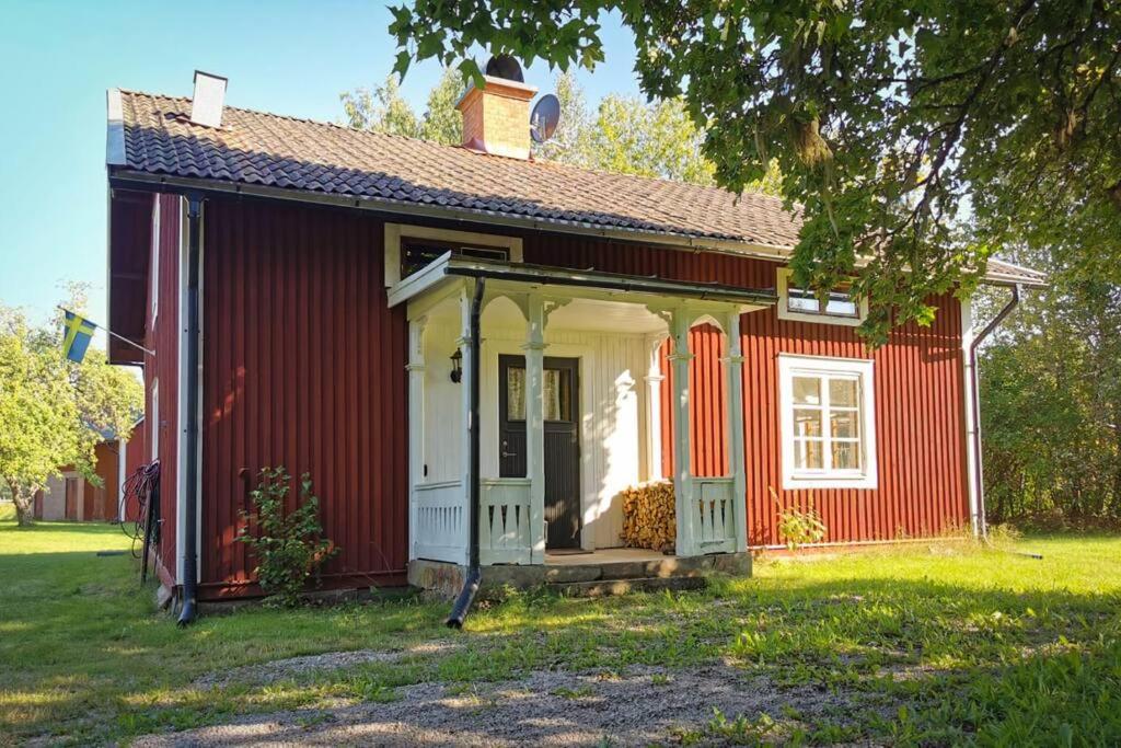 a red and white house with a porch at Nilsstugan in Råda