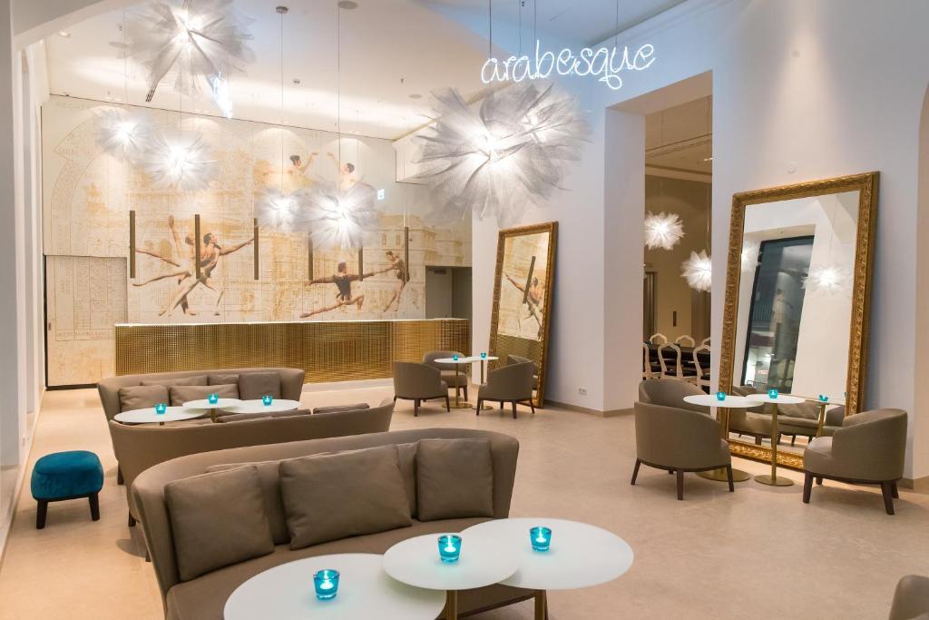 a waiting room with tables and chairs and a mirror at Motel One Wien-Staatsoper in Vienna