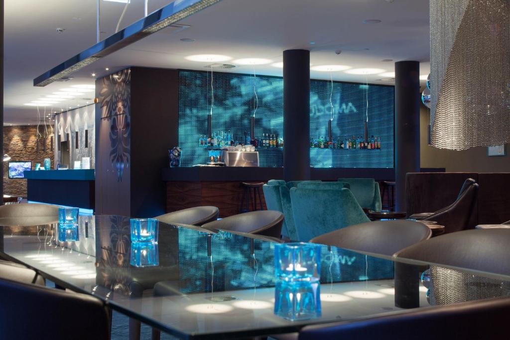 ein Restaurant mit einer Bar mit blauem Glas in der Unterkunft Motel One Frankfurt Messe in Frankfurt am Main