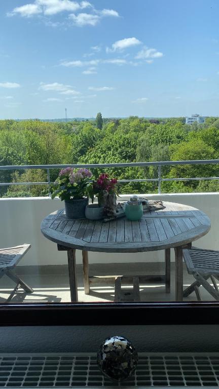 una mesa de madera en un balcón con flores en Kleine zimmer in luxus wohnung en Schenefeld