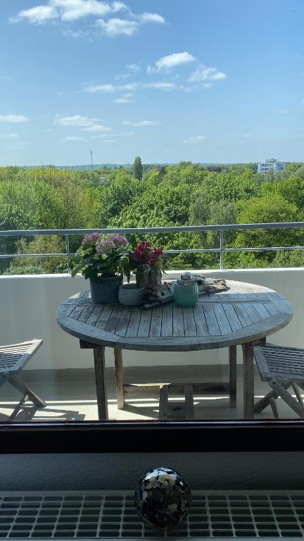 uma mesa de madeira numa varanda com flores em Kleine zimmer in luxus wohnung em Schenefeld