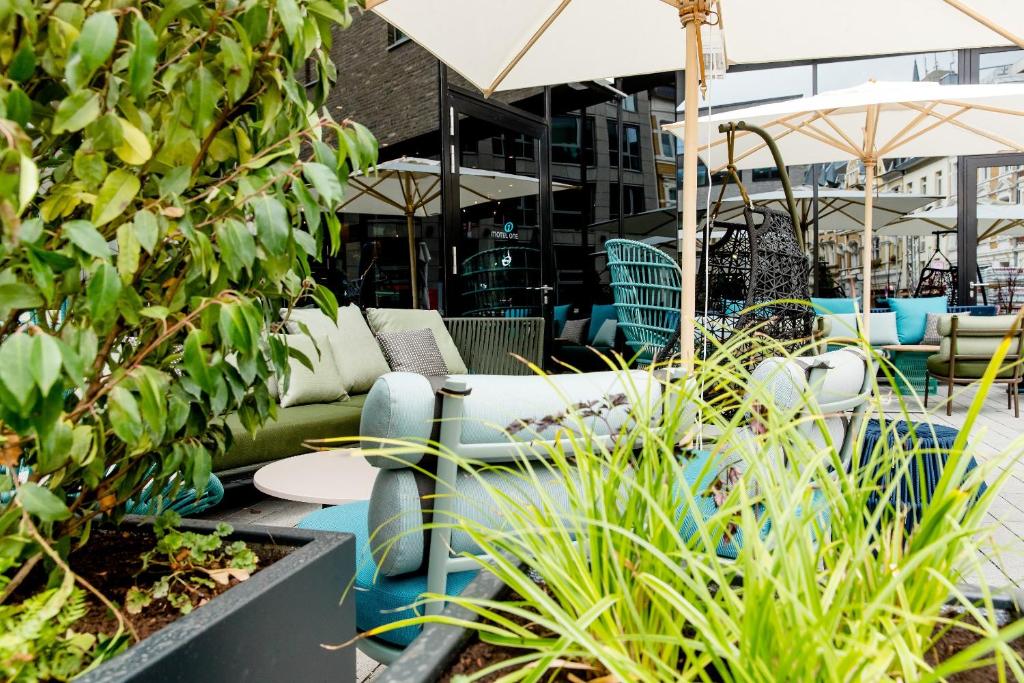 a patio with chairs and umbrellas and plants at Motel One Bonn-Hauptbahnhof in Bonn