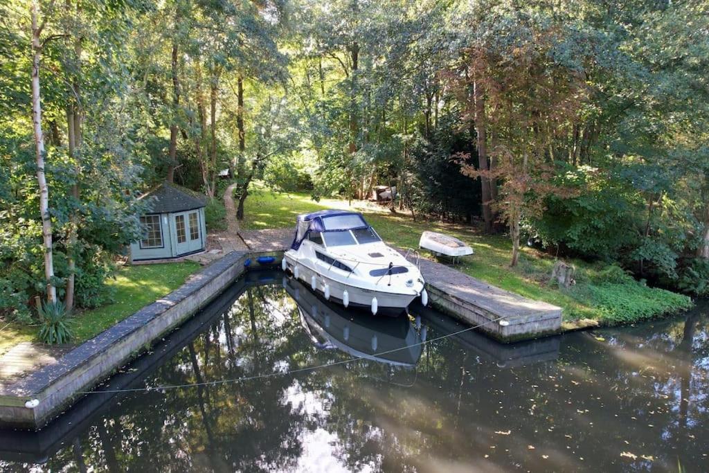 a boat is docked at a dock in the water at Waterside Cottage - Hot Tub, Mooring, Arcade, Bar in Neatishead