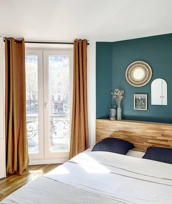 a bedroom with a bed with blue walls and a window at Charmant appartement parisien, spacieux & lumineux in Paris