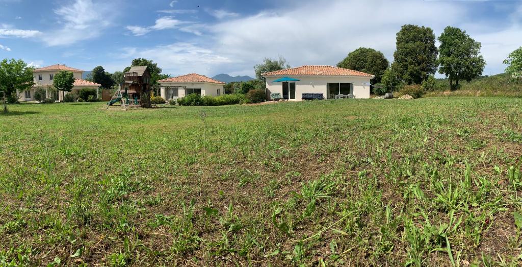 a large field with a house in the background at A PIAZZOLA in Petreto-Bicchisano