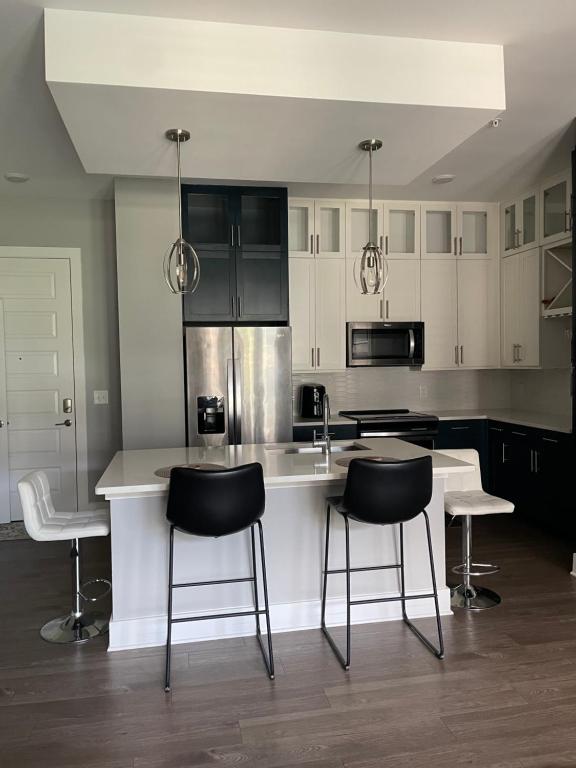 een keuken met zwarte en witte kasten en zwarte stoelen bij Home away from home in Decatur