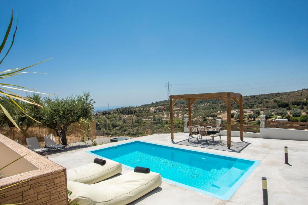 a swimming pool with chairs and a table on a patio at Villa Tranquility in Psinthos