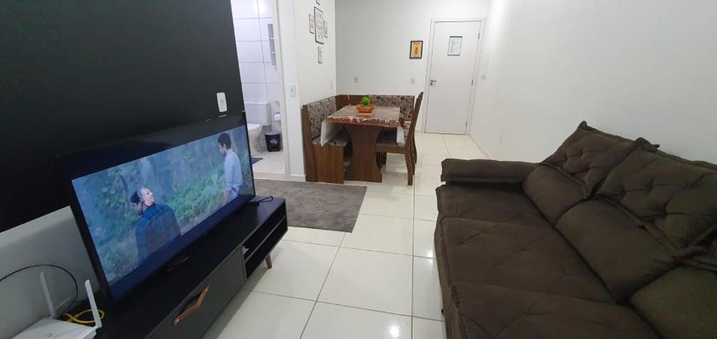 uma sala de estar com um sofá e uma televisão de ecrã plano em Condomínio Residencial Mar Azul em Imbituba