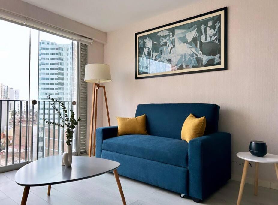 a living room with a blue couch and a table at Encantador apartamento 2 habitaciones/ Cochera / Gimnasio in Lima
