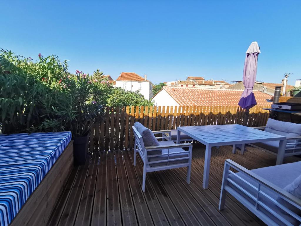 eine Terrasse mit 2 Stühlen, einem Tisch und einem Sonnenschirm in der Unterkunft T3 terrasse classé 4 étoiles le Poulpe 200m front de mer in Banyuls-sur-Mer