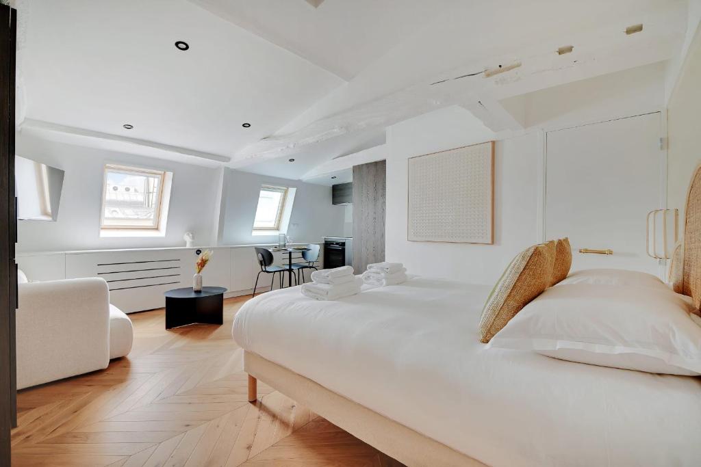 a white bedroom with a large bed and a living room at Brand New Modern Studio in Central Paris - 2P - B6 in Paris