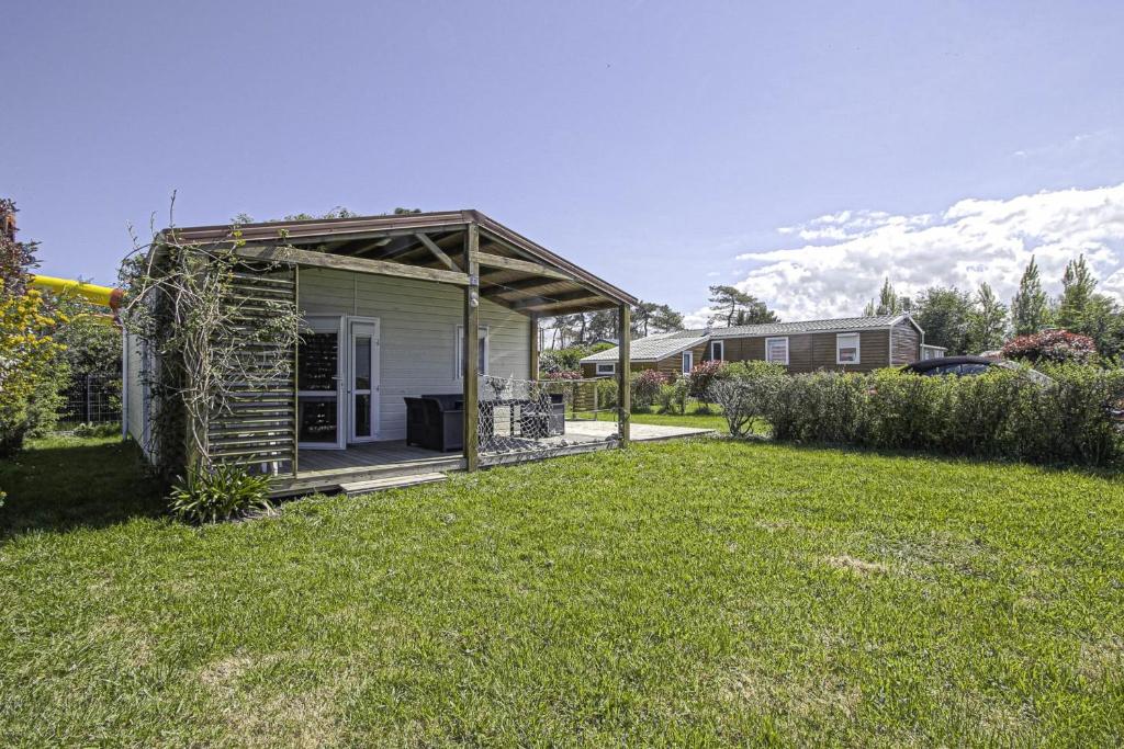 un petit hangar avec terrasse couverte dans une cour dans l'établissement La Coquille PRL 37, à Grandcamp-Maisy