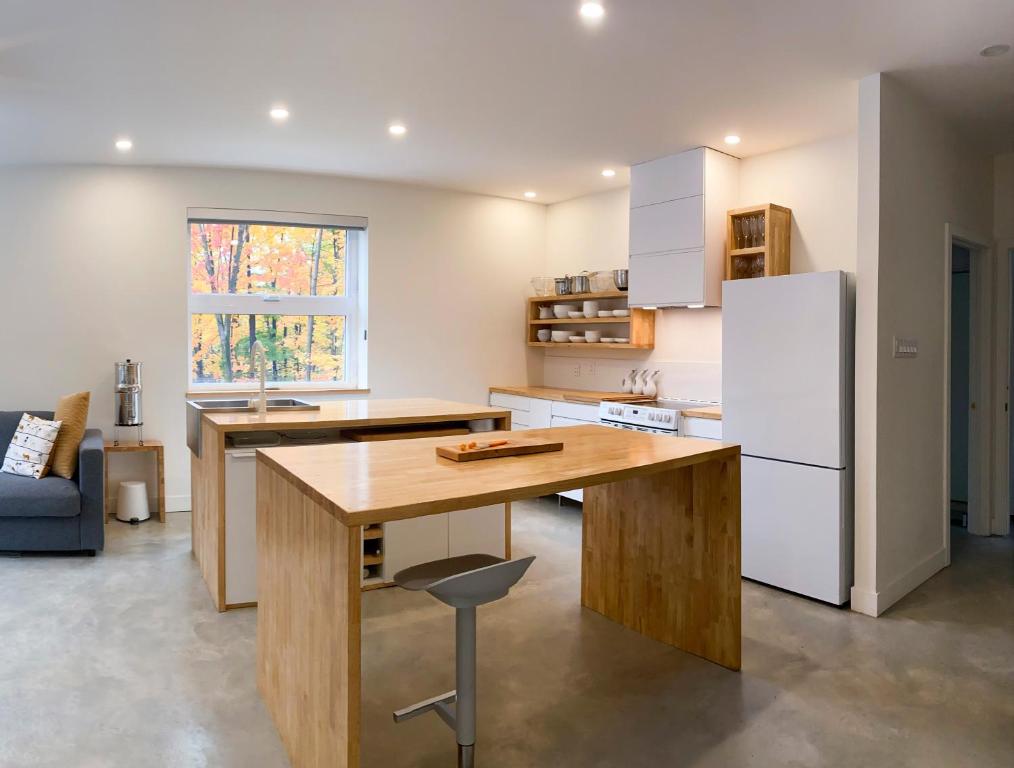 a kitchen with a wooden table and a refrigerator at Le Camp Caché Shefford in Shefford