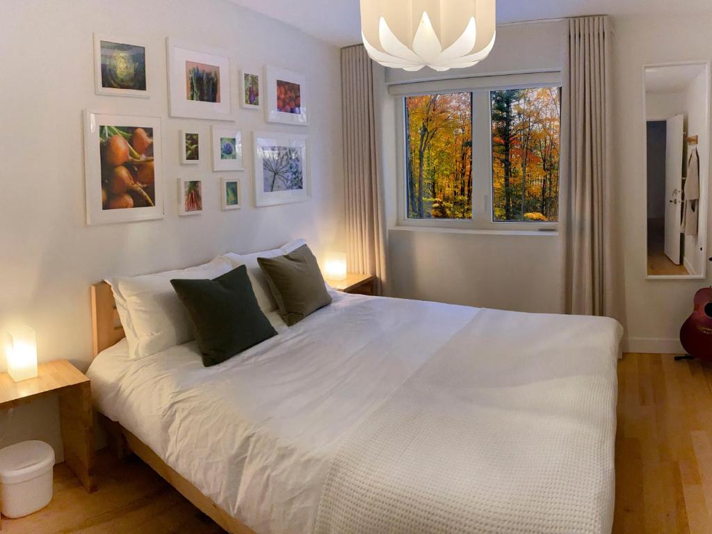 a bedroom with a large white bed and a window at Le Camp Caché Shefford in Shefford