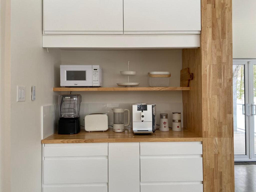 a kitchen with white cabinets and white appliances at Le Camp Caché Shefford in Shefford