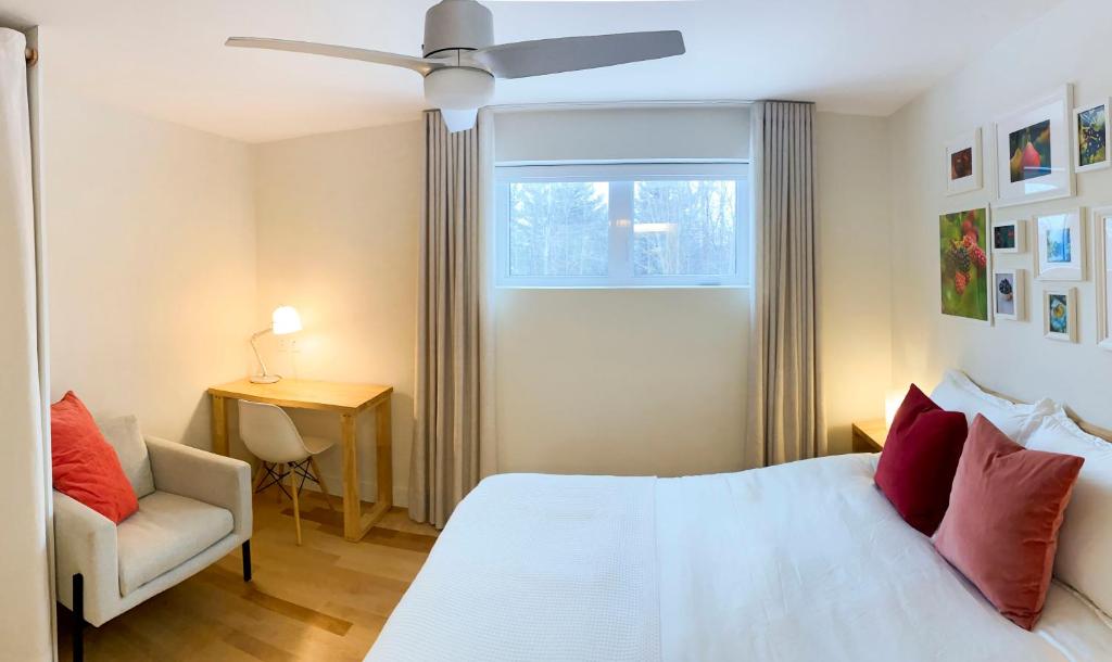 a bedroom with a white bed and a chair and a window at Le Camp Caché Shefford in Shefford