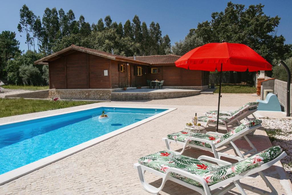 ein Pool mit zwei Stühlen und einem roten Sonnenschirm in der Unterkunft Casa da Poesia in Pedreiras