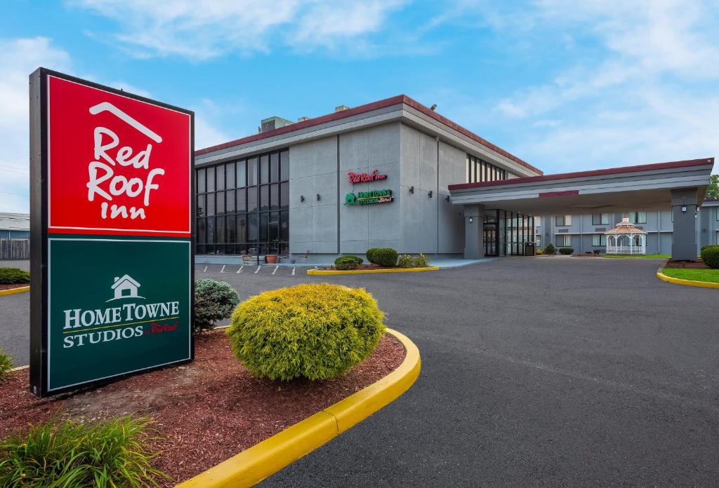 a red roof inn sign in front of a building at HomeTowne Studios by Red Roof Painted Post in Painted Post