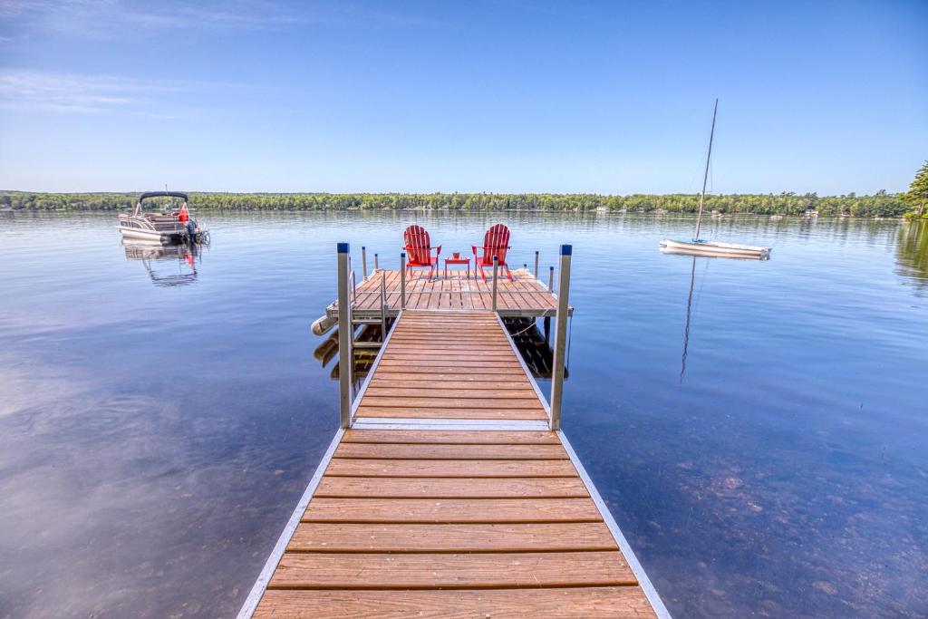 a dock with two chairs and a boat on a lake at Lakeside Cottages on Toddy Pond in Orland