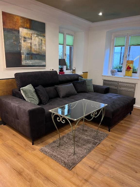 a living room with a black couch and a glass table at Ferienwohnung am Kirchberg Europa-Park Spassbad-Rulantica-Schwarzwald ,Frankreich, in Ettenheim