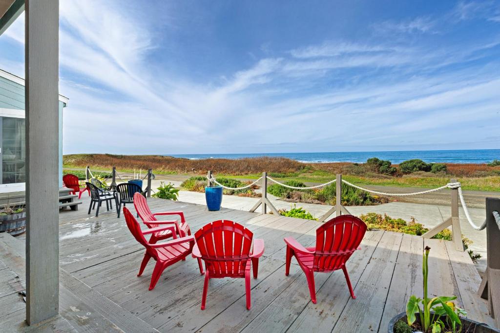 a deck with red chairs and a view of the ocean at Sea Dream and Sand Dollar Suite in Fort Bragg