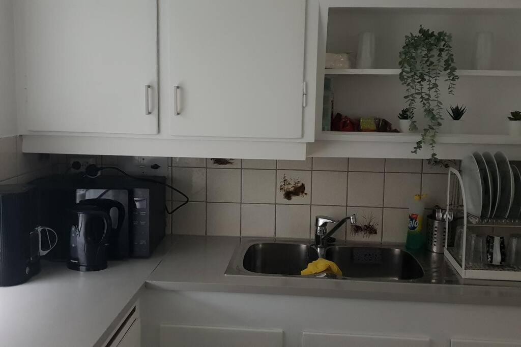 eine Küchentheke mit einer Spüle und weißen Schränken in der Unterkunft Koselig leilighet med balkong og parkering. in Stavanger