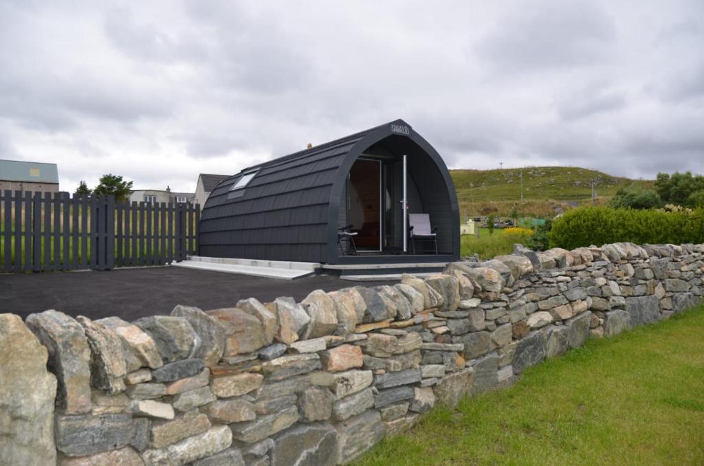 una casa a cupola nera con un muro di pietra di Kelly's Pod a Garynahine