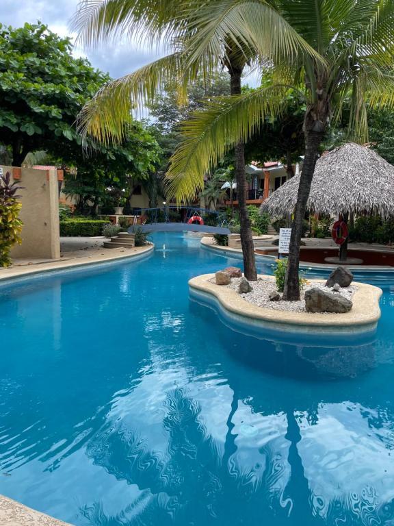 una piscina con palmeras en un complejo en Cocomarindo Condo #72 en Coco