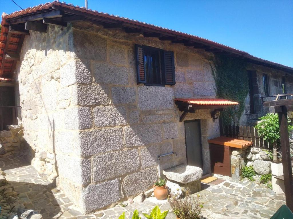 una casa de piedra con un banco delante en Ninho do Corvo da Urgueira, en Urgueira